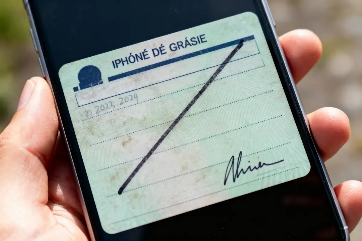 Carte humoristique sur écran de téléphone, texte parodique "IPHONÉ DÉ GRÁSIE", signature visible.