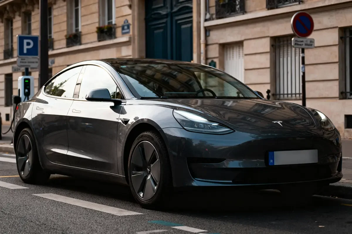 Voiture électrique grise garée dans une rue urbaine avec immeubles en arrière-plan.