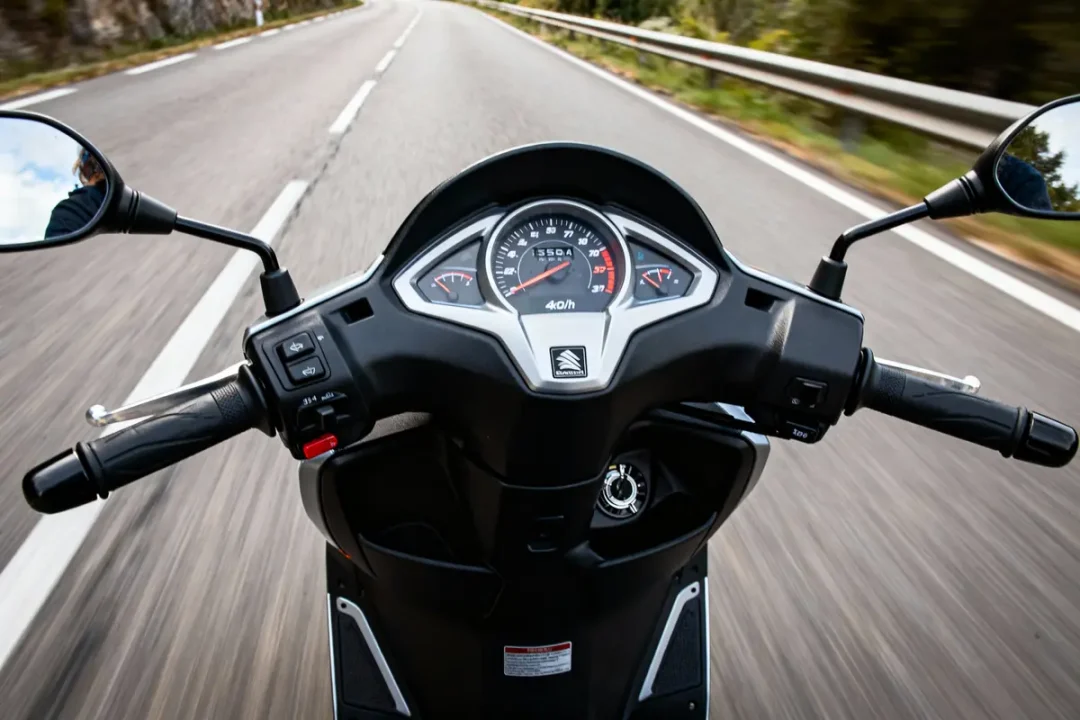 Vue depuis un guidon de scooter roulant vite sur route vide et sinueuse, ciel bleu visible.