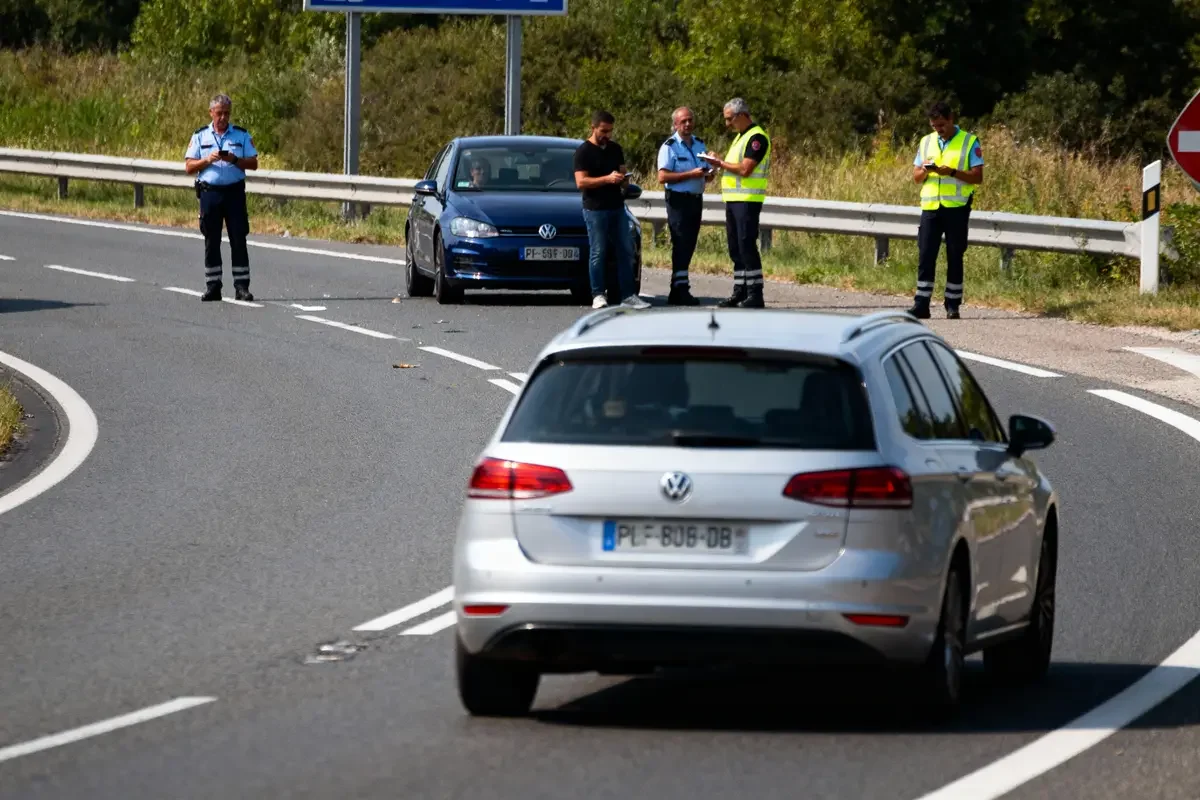 Voitures arrêtées sur autoroute avec policiers et personnel en gilets réfléchissants discutant sur la chaussée.