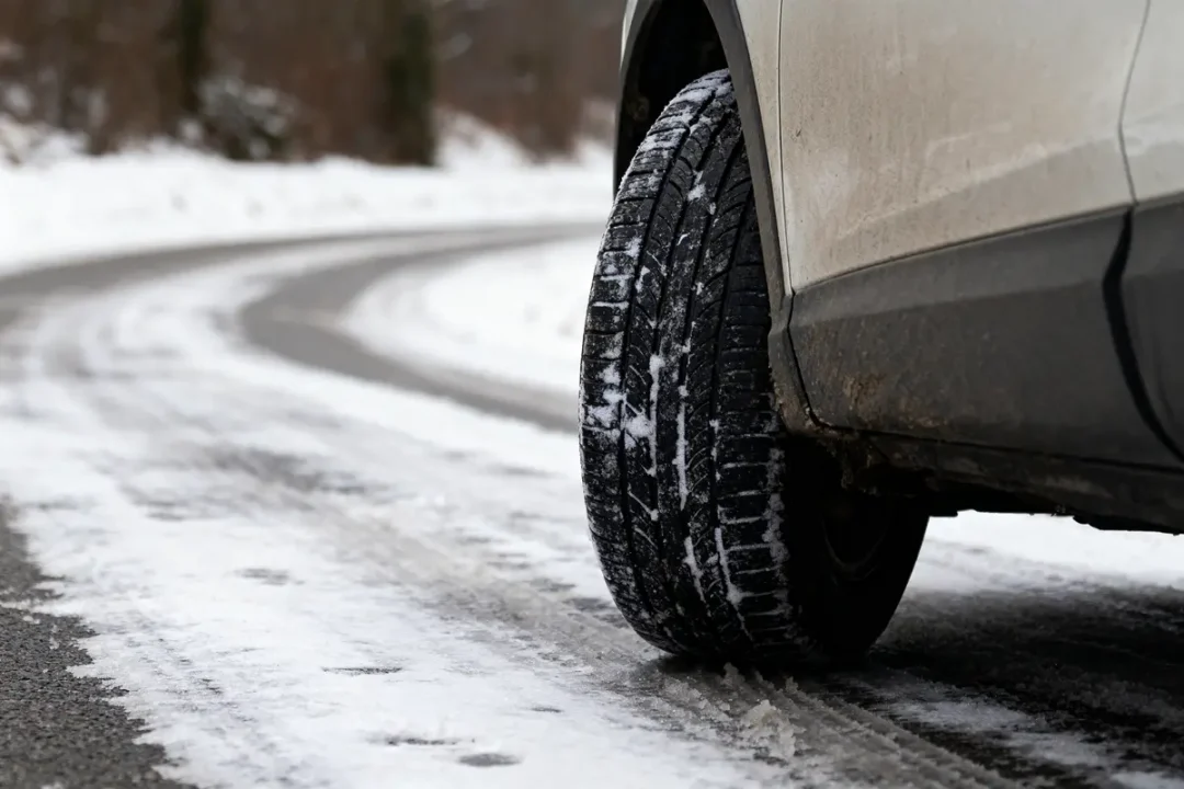 Voiture en mouvement soulevée sur route mouillée avec flaques d'eau, environnement naturel en arrière-plan.