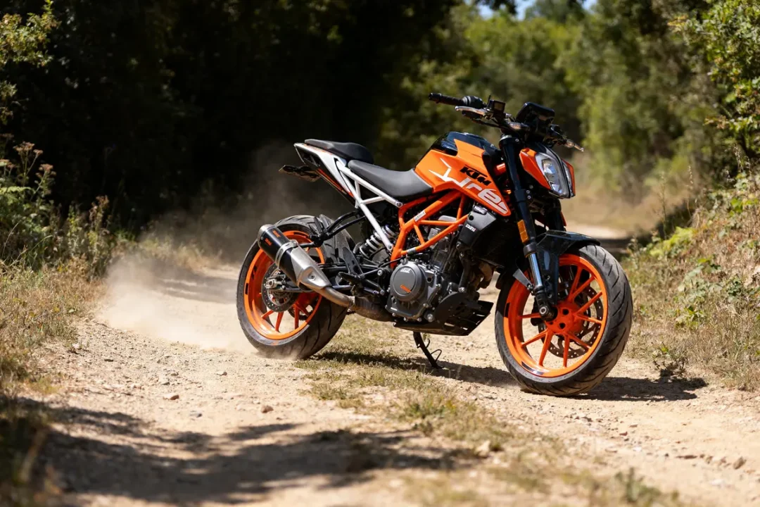Moto KTM Duke 125 orange en mouvement sur un chemin entouré de végétation luxuriante