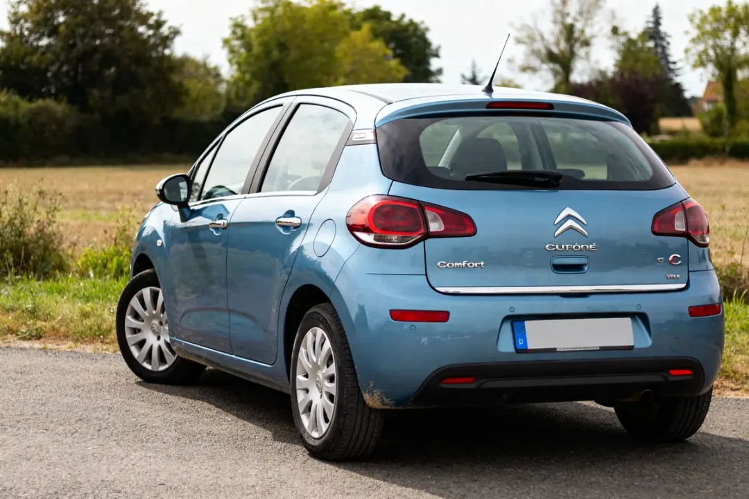 Voiture bleue Citroën C3 2012 garée sur route de campagne verdoyante.