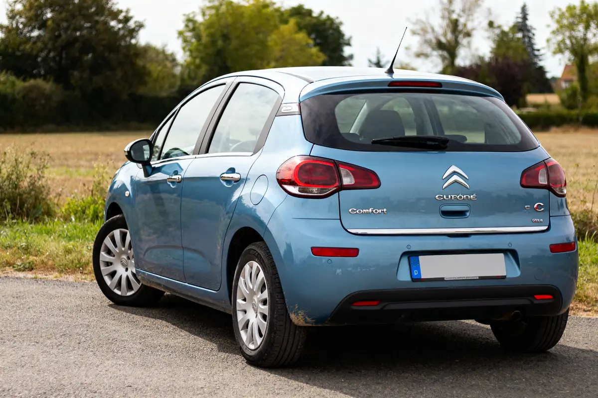 Voiture bleue Citroën C3 2012 garée sur route de campagne verdoyante.