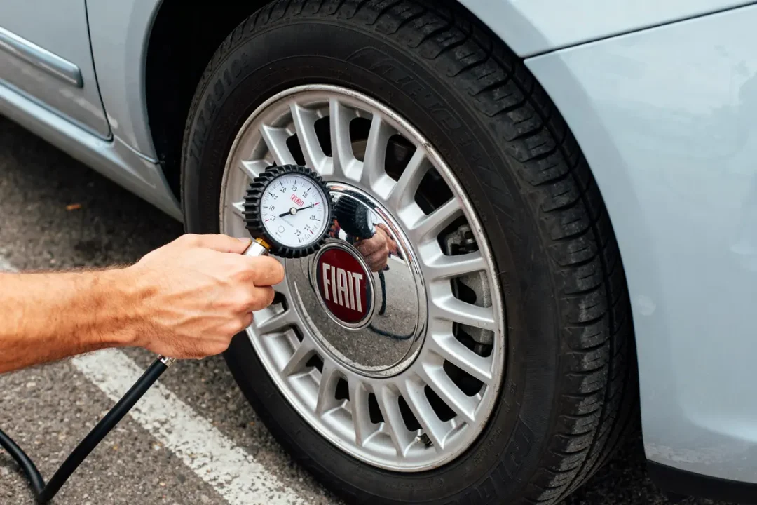 Main vérifiant pression de pneu pour Fiat 500 avec un manomètre sur la roue