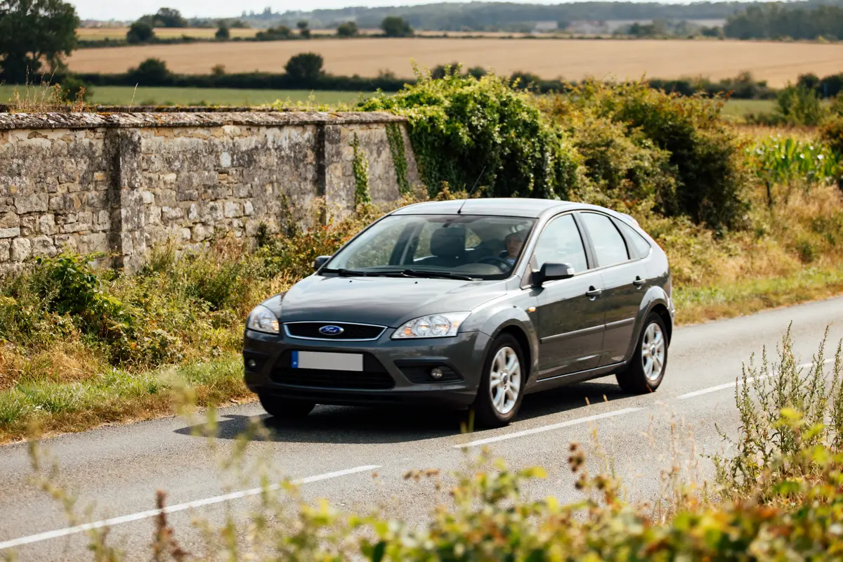 Voiture grise 08 Ford Focus roulant sur une route de campagne bordée de végétation