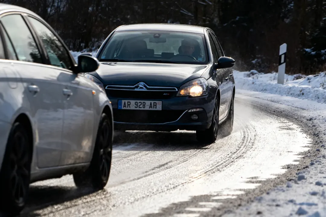 Voitures circulant sur route enneigée avec ASR sur voiture noire Citroën C5 visible