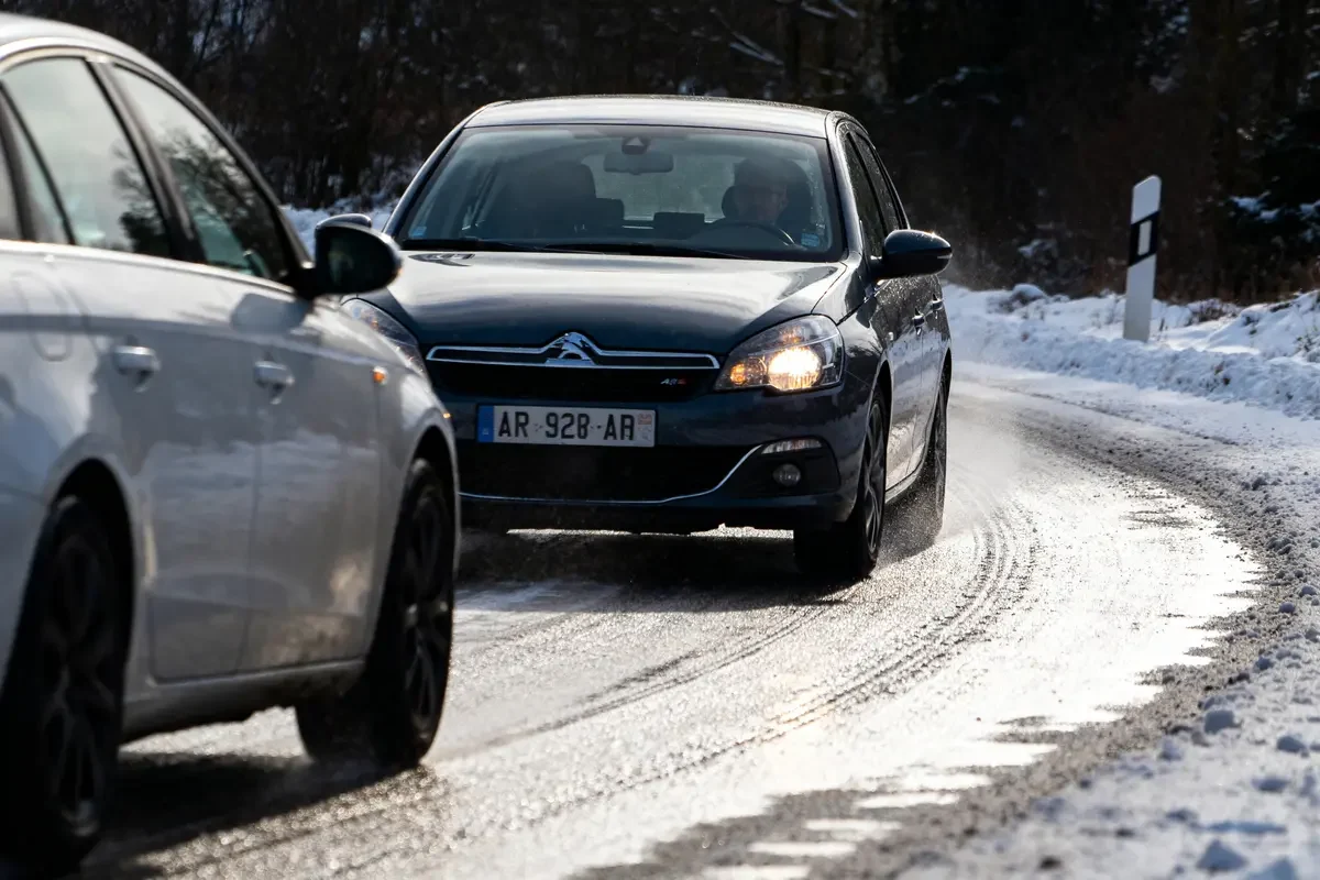 Voitures circulant sur route enneigée avec ASR sur voiture noire Citroën C5 visible