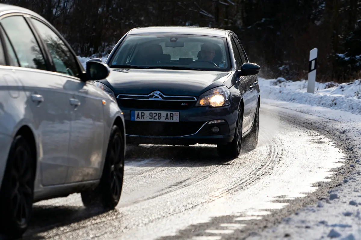 Voitures circulant sur route enneigée avec ASR sur voiture noire Citroën C5 visible