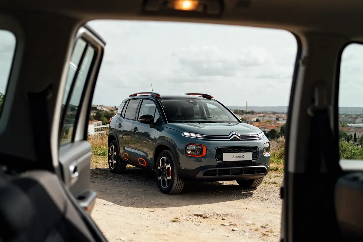 Vue extérieure d'un Citroën C3 Aircross sur chemin rural depuis l'intérieur d'une voiture