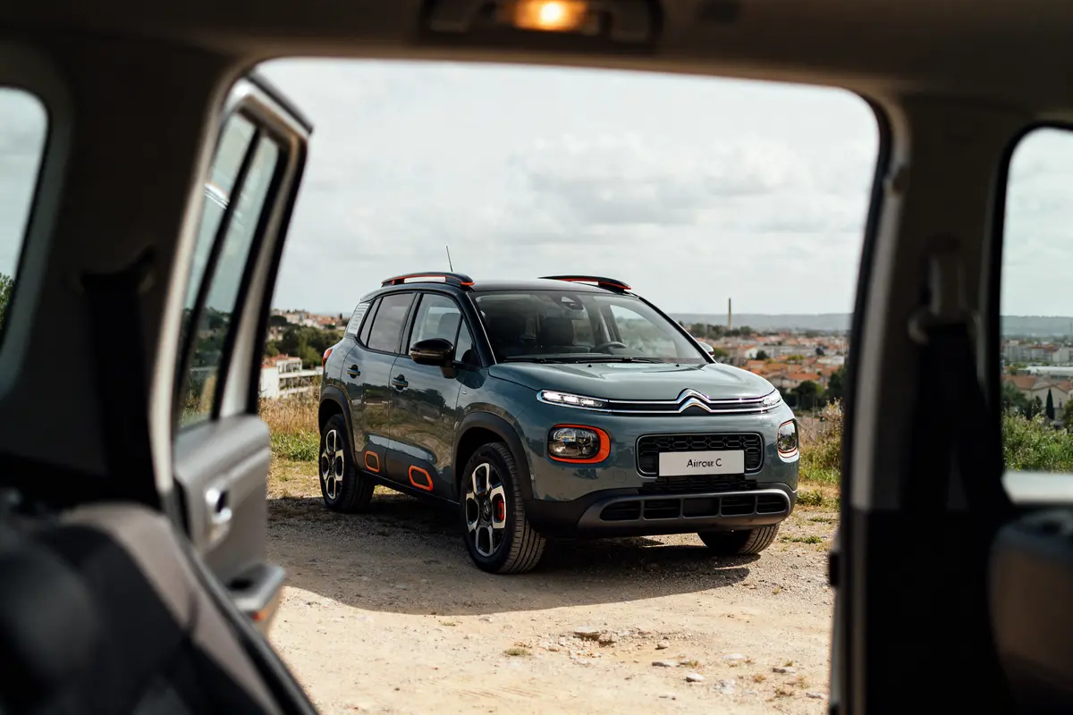 Vue extérieure d'un Citroën C3 Aircross sur chemin rural depuis l'intérieur d'une voiture
