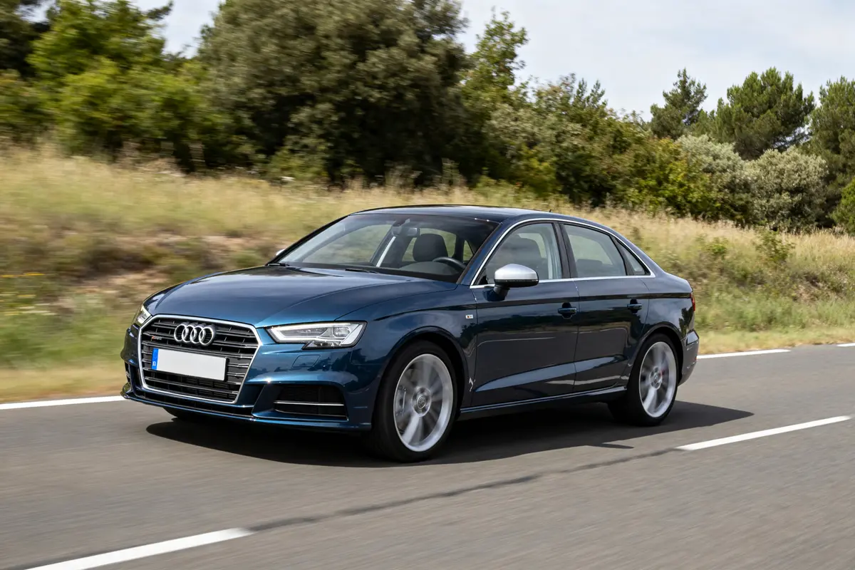 Voiture bleue Audi A3 roulant sur une route arborée en extérieur journée.