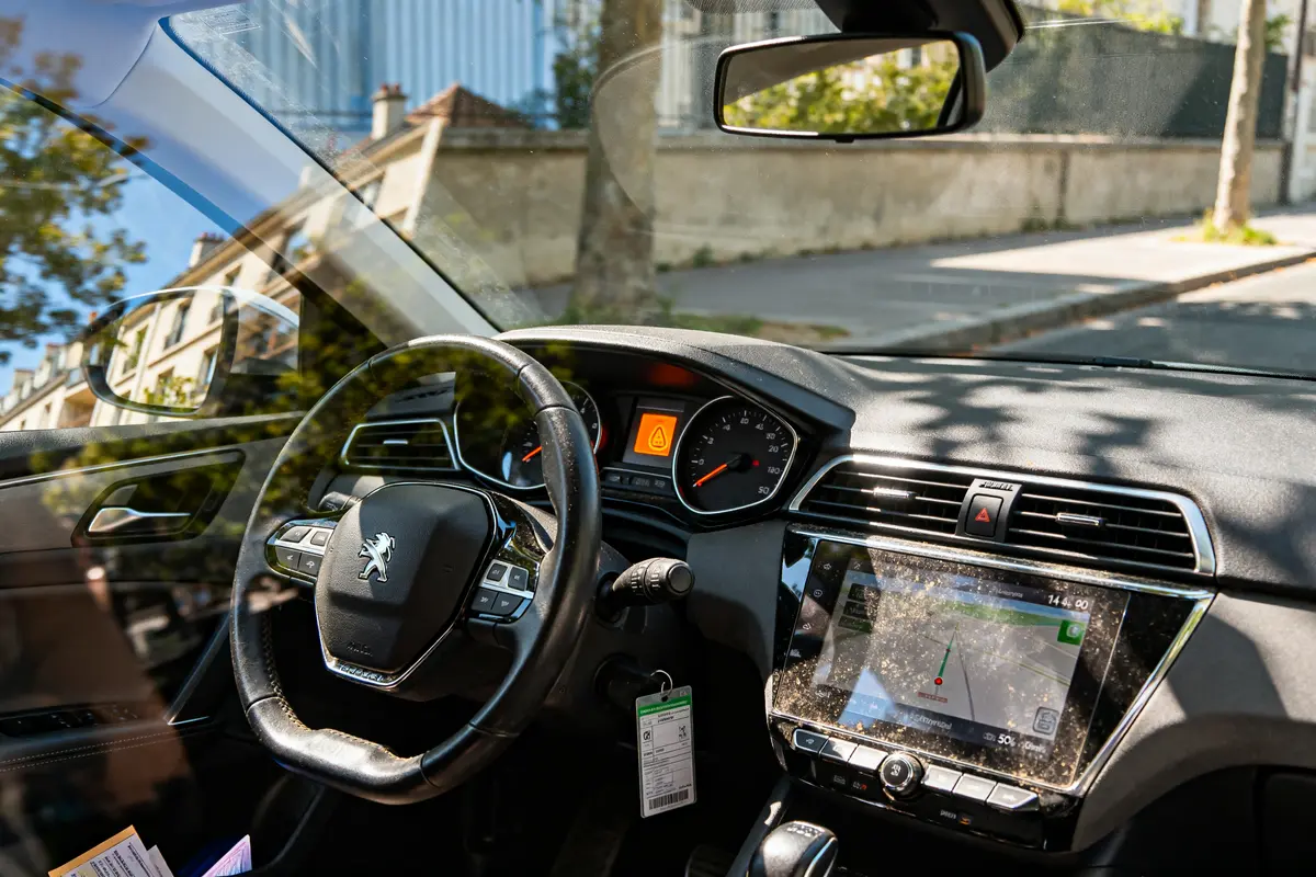 Tableau de bord voiture avec voyant antipollution allumé et perte de puissance affichée.