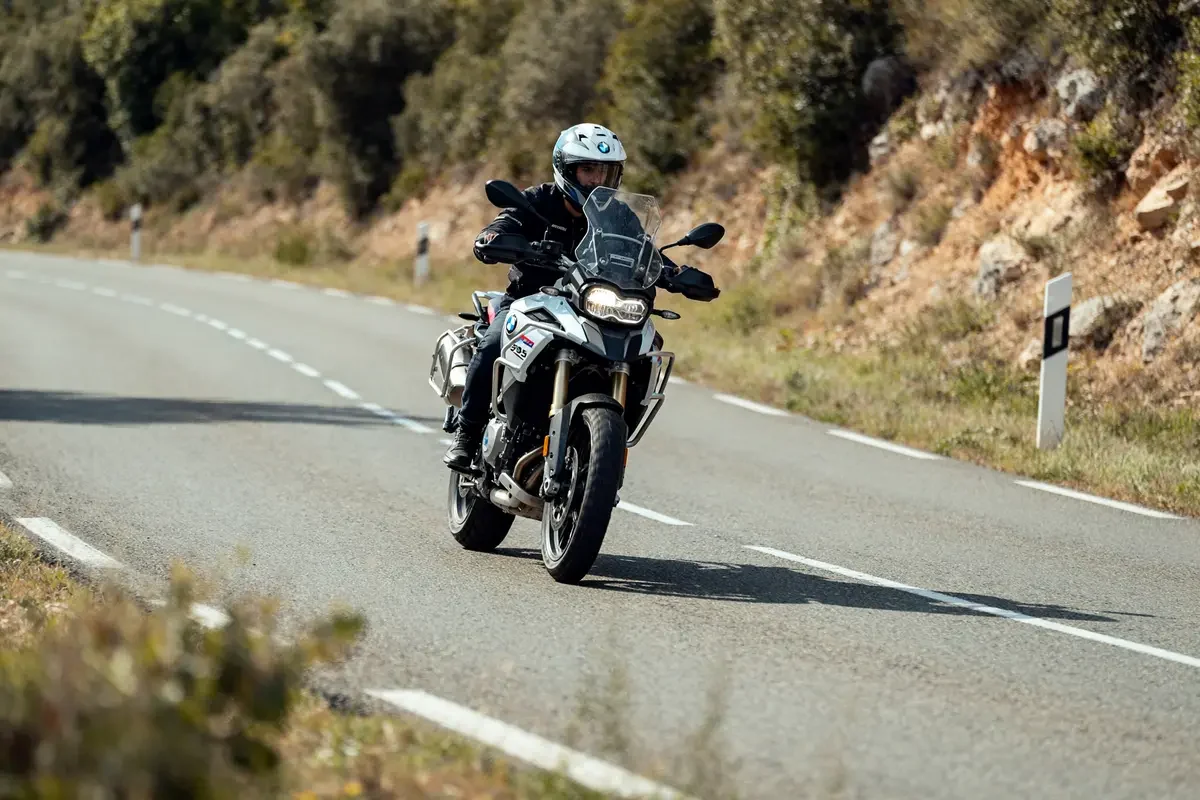 Motard sur route sinueuse avec une BMW F 900 XR, en plein virage en campagne