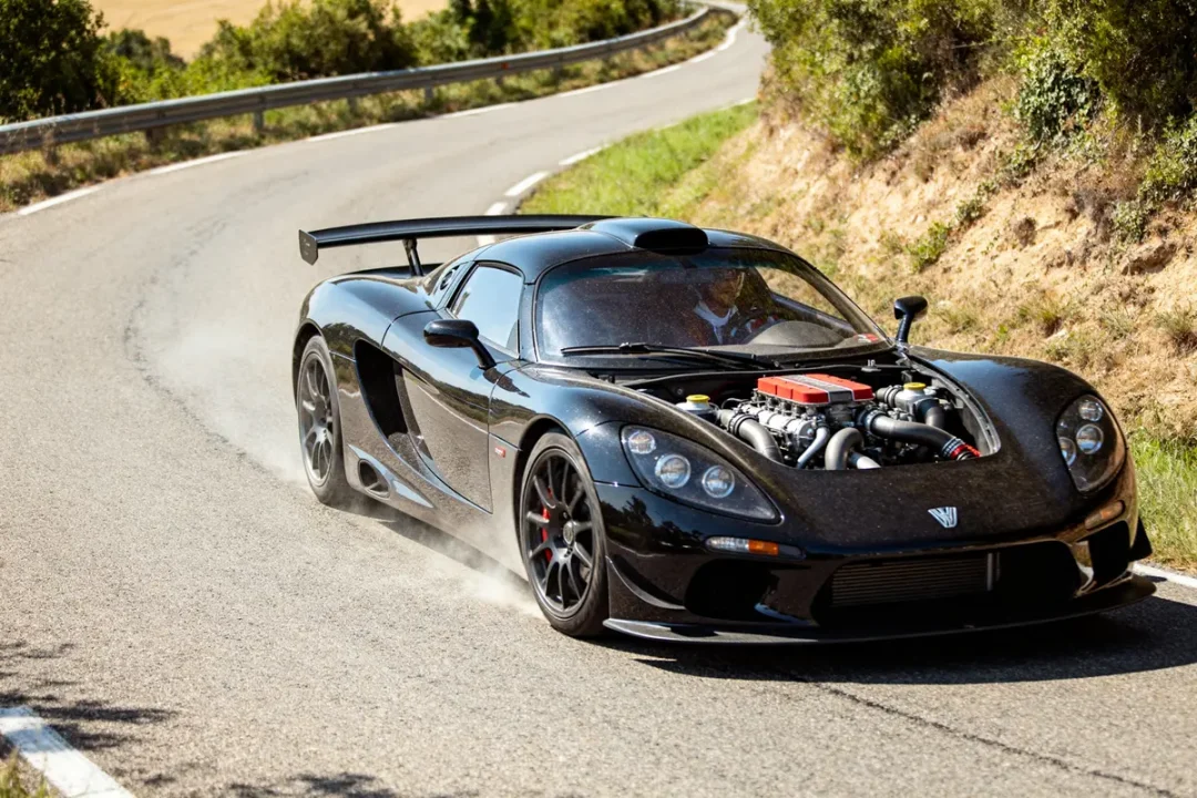 Hennessey Venom GT Supercar noire roulant sur une route sinueuse en pleine vitesse