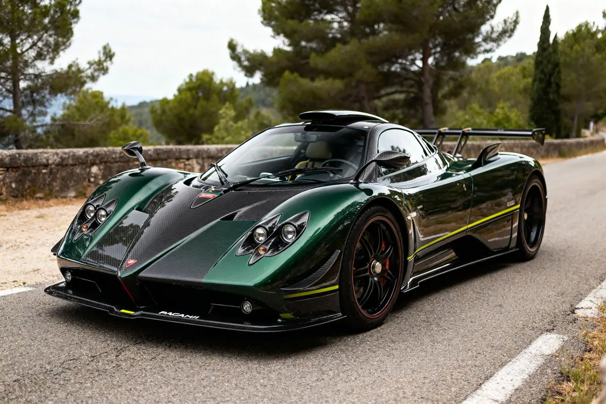 Supercar Pagani Zonda verte et noire sur une route bordée d'arbres