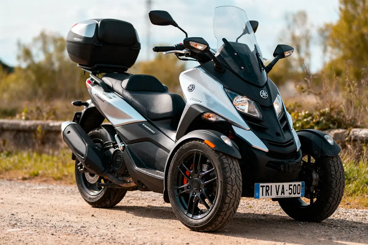 Scooter Yamaha Tricity 500 garé sur chemin, neuf, avec prix compétitif visible sur la plaque