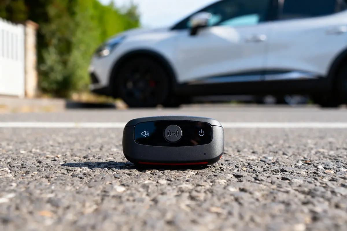 Boîtier d'alarme pour voitures posé sur route avec voiture floue à l'arrière-plan