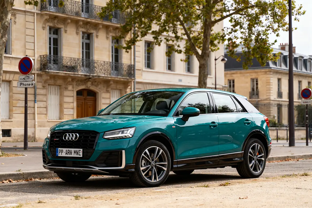 Voiture Audi Q2 d'occasion turquoise stationnée devant immeubles anciens sur rue bordée d'arbres