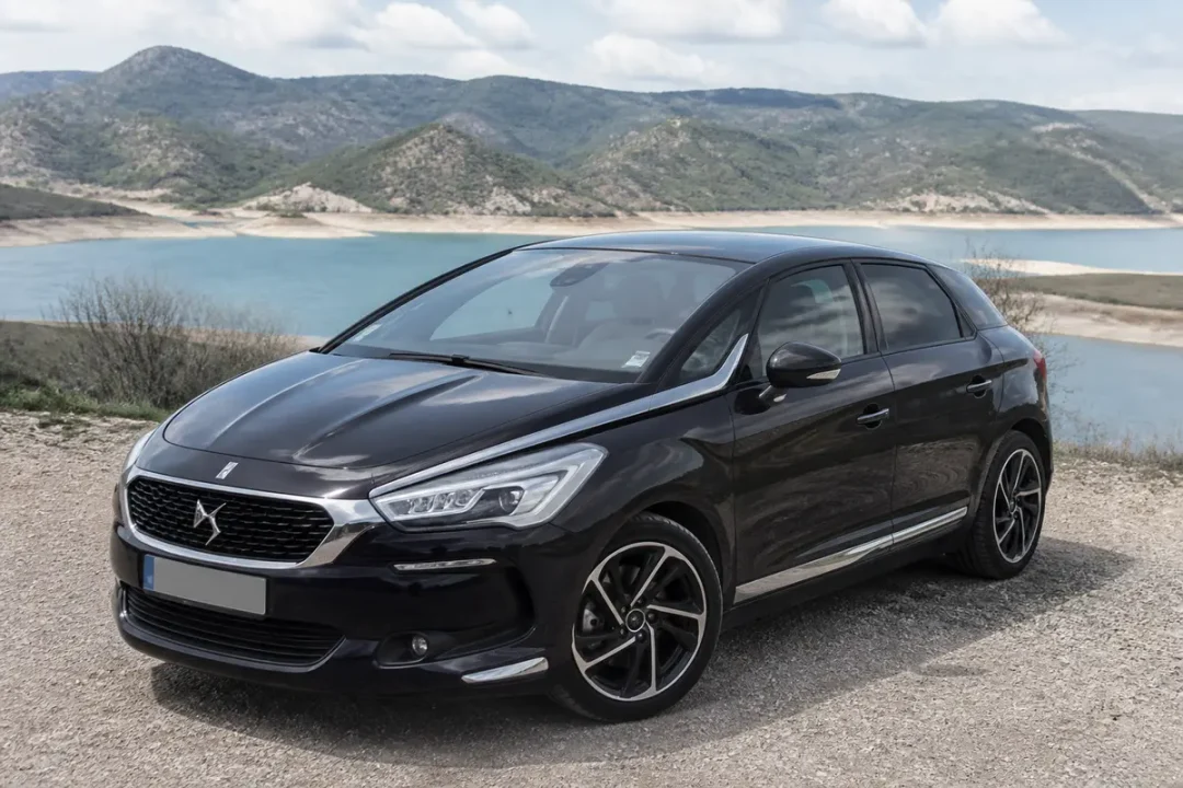Voiture DS5 noire garée près d'un lac en arrière-plan montagneux