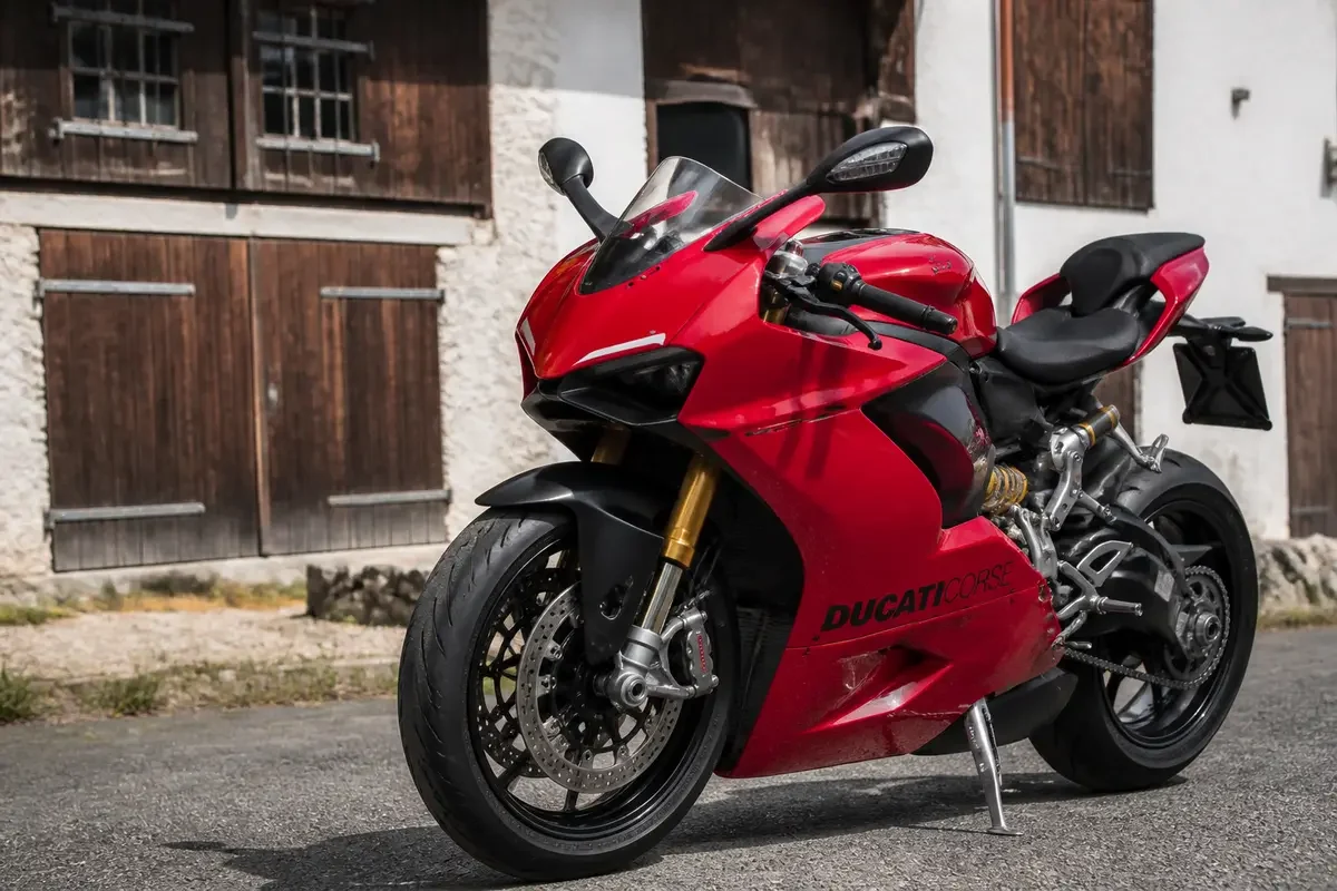 Moto rouge d'une marque de moto italienne stationnée devant une grange en bois.