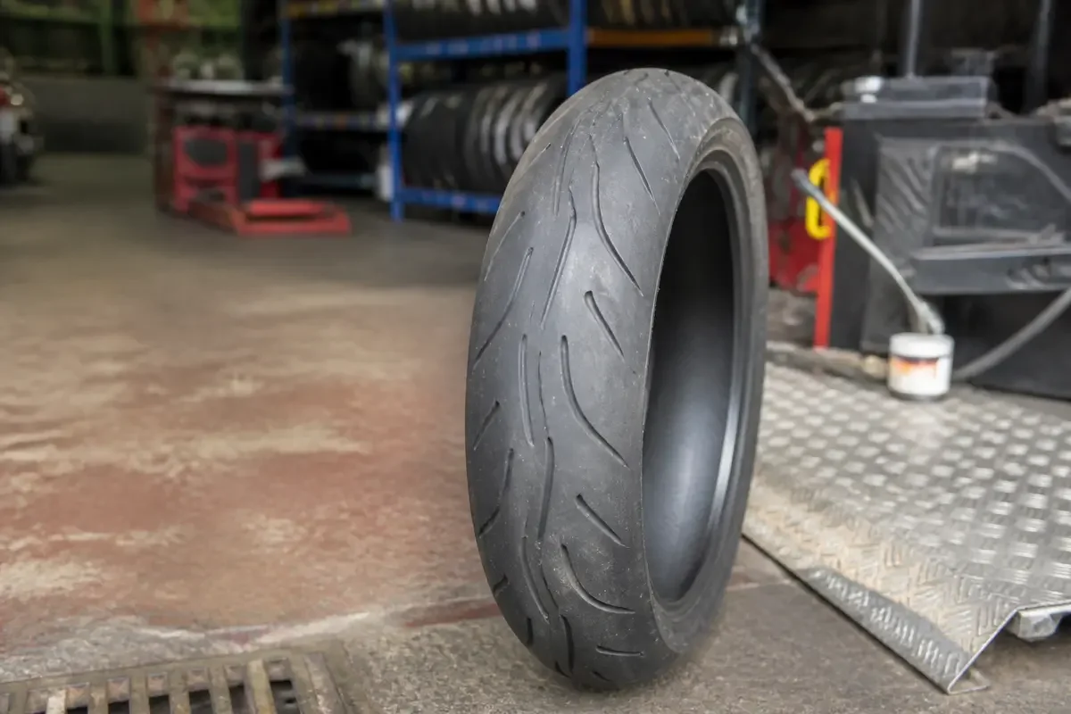 Pneu de moto abordable posé dans un atelier avec des étagères remplies de pneus.
